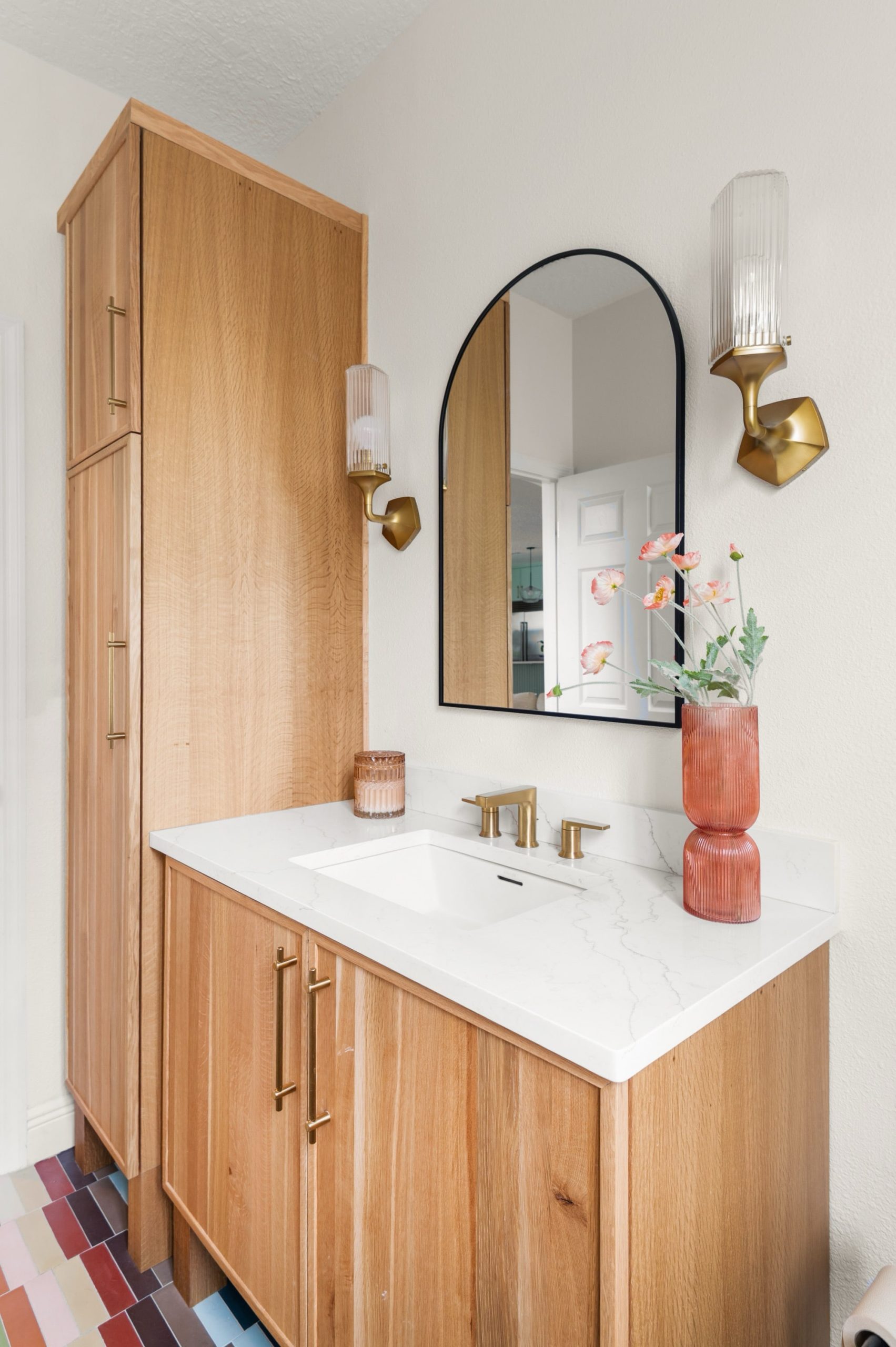 powder room remodel natural wood vanity and coordinating storage cabinetry, brass fixtures and arched mirror